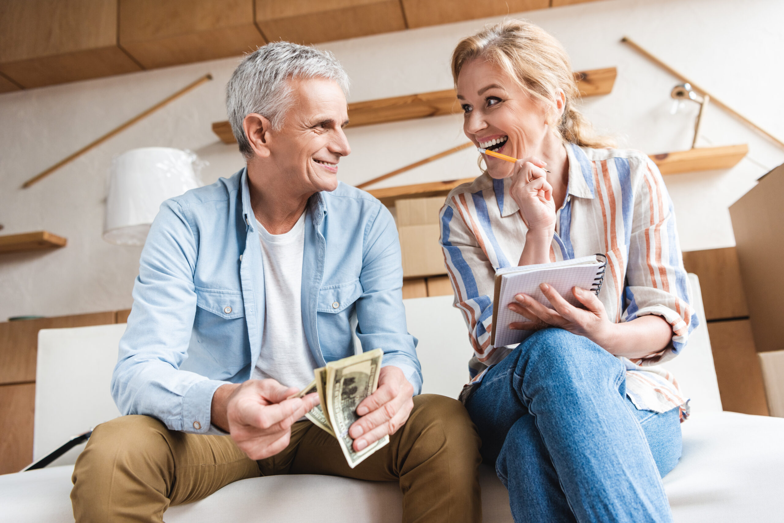 happy elderly couple counting money and laughing while moving home