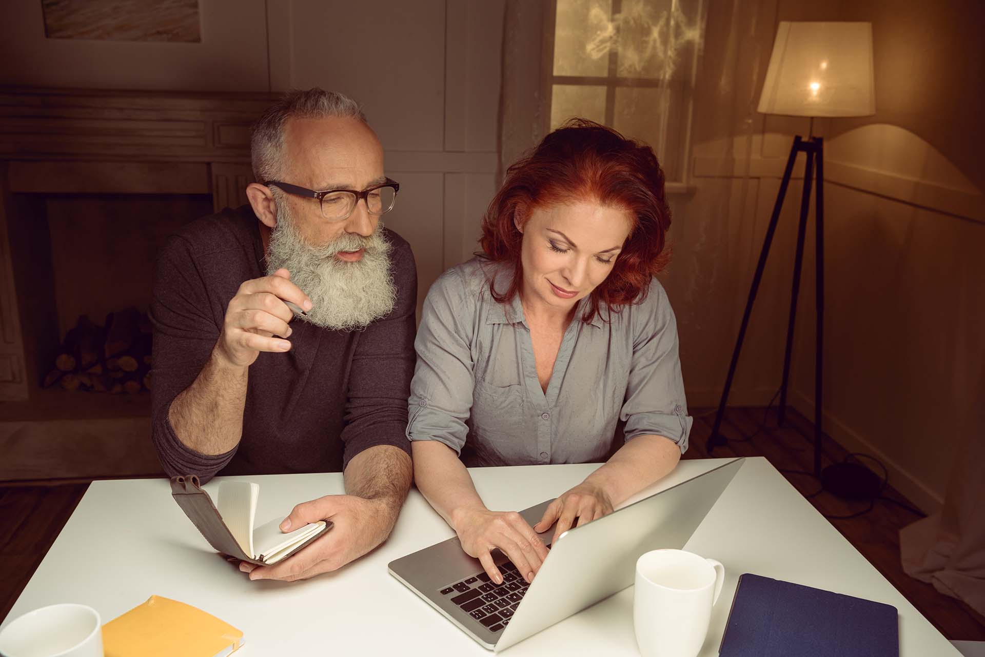 middle aged couple working on laptop while sitting at table