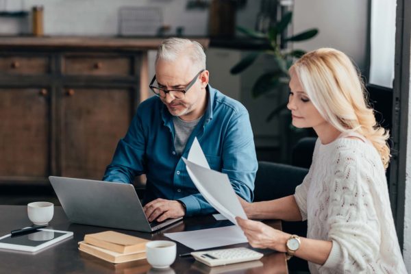 handsome man in glasses using laptop near attractive wife lookin how much life insurance do i need